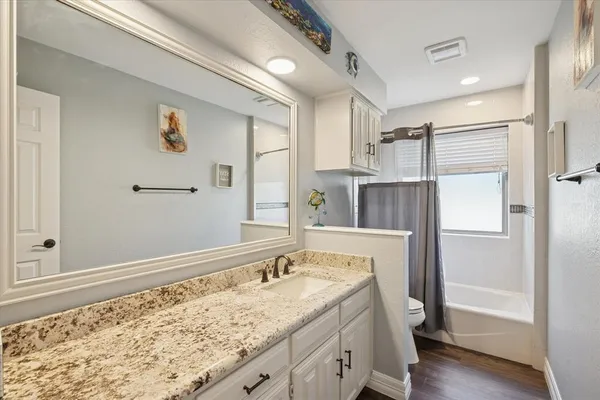 a bathroom with a granite countertop sink and a bathtub