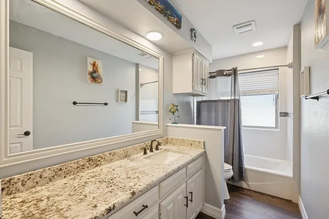 a bathroom with a granite countertop sink and a bathtub