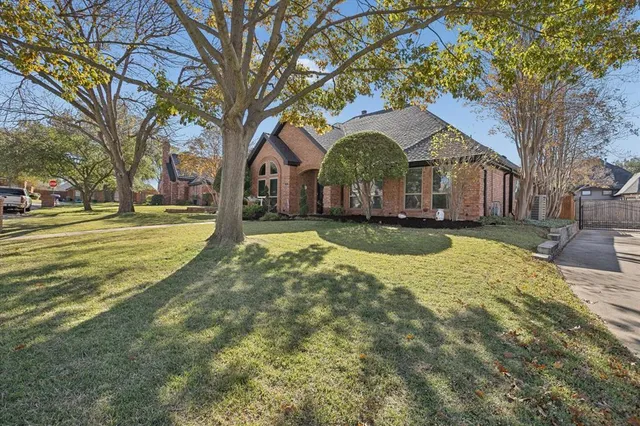 a front view of a house with a yard and large trees