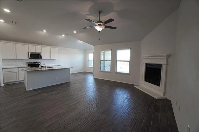 a view of an empty room with a kitchen and wooden floor