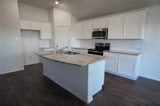 a kitchen with granite countertop white cabinets sink and stainless steel appliances
