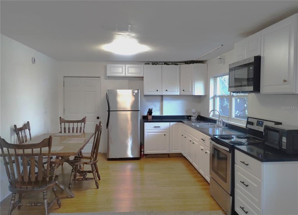 417 East Main Street Dundee, FL 33838 - Photo 10 of 24 a kitchen with stainless steel appliances granite countertop a refrigerator a stove a sink dishwasher a dining table and chairs with wooden floors