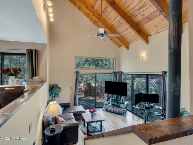 a living room with furniture a flat screen tv and a floor to ceiling window