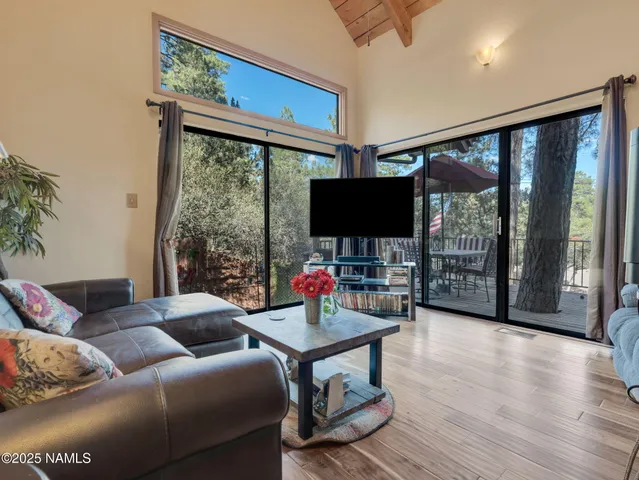 a living room with furniture a flat screen tv and a floor to ceiling window