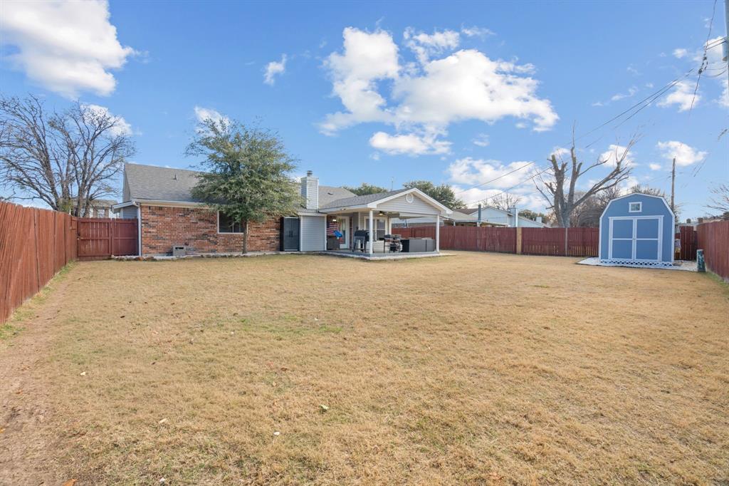7629 Cedarhill Road Watauga, TX 76148 - Photo 30 of 33 Expansive backyard featuring a large lawn, wood privacy fencing, a covered patio area, and a standalone storage shed