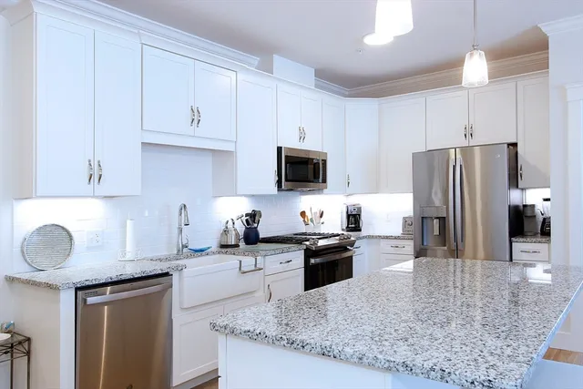 a kitchen with granite countertop a sink a counter top space appliances and cabinets