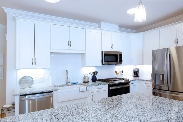 a kitchen with granite countertop a stove sink and refrigerator