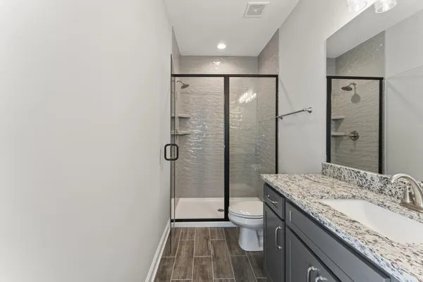 a bathroom with a granite countertop sink a mirror and shower