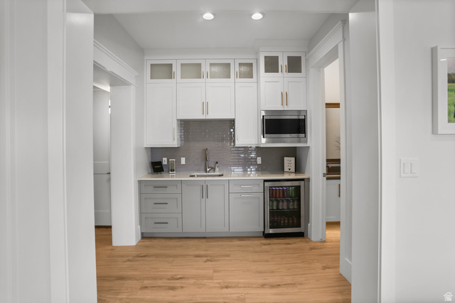 1354 South 800 East Mapleton, UT 84664 - Photo 88 of 129 Dual tone kitchen with dual tone cabinets, glass fronted cabinets, wine cooler, recessed lighting, and light wood finished floors