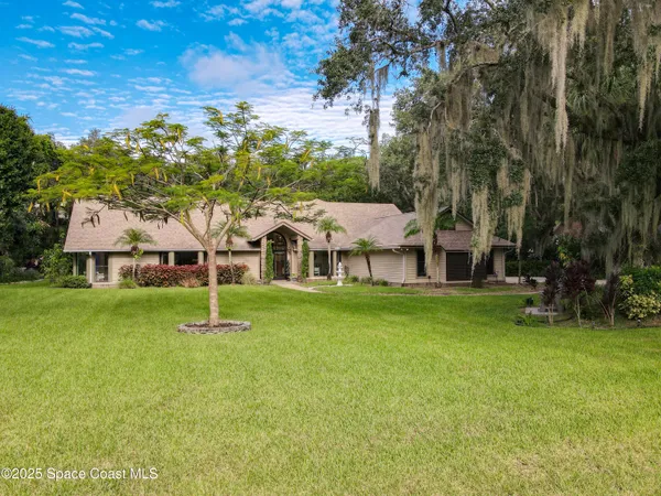 a view of a house with a big yard and large trees