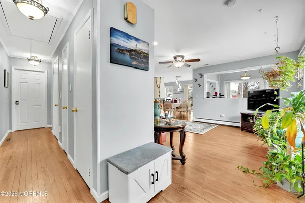 a view of a hallway to a livingroom and a dining room with furniture wooden floor and a chandelier