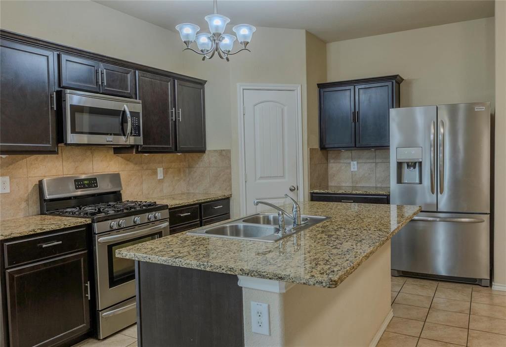 5157 Grayson Ridge Drive Fort Worth, TX 76179 - Photo 5 of 34 a kitchen with granite countertop a refrigerator stove and microwave