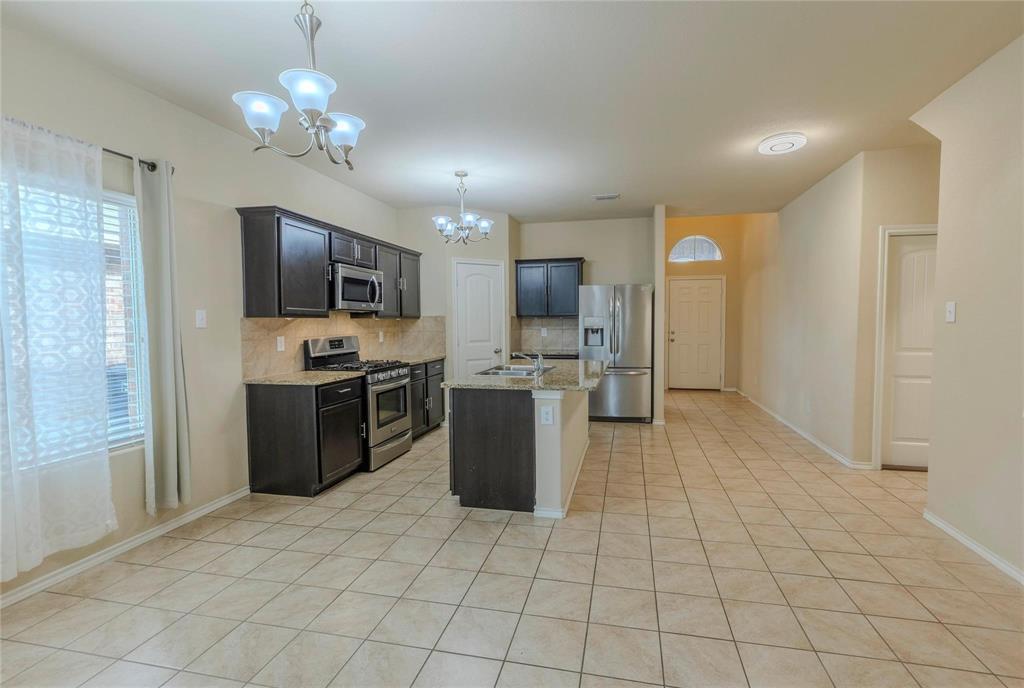5157 Grayson Ridge Drive Fort Worth, TX 76179 - Photo 7 of 34 a kitchen with stainless steel appliances kitchen island granite countertop a refrigerator and a stove top oven