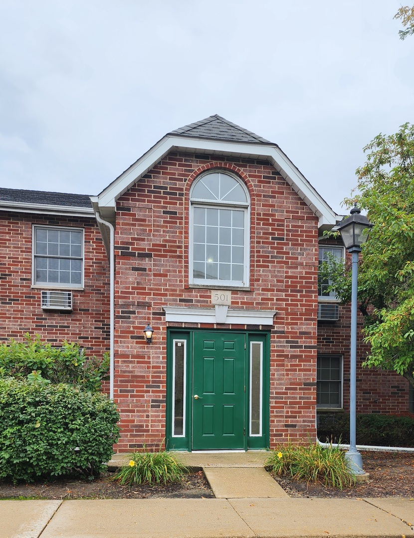 501 Leah Lane, Unit 2A Woodstock, IL 60098 - Photo 1 of 13 a front view of a house with garden