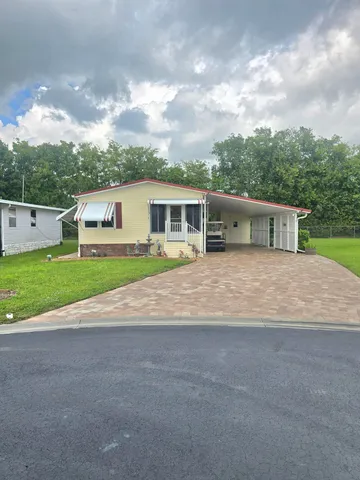 a view of a house with a yard and large trees