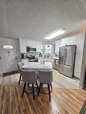 a kitchen with kitchen island a stove a table and chairs in it