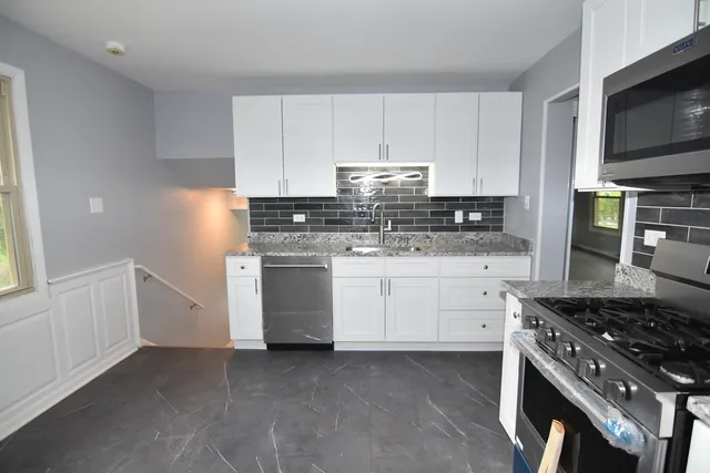 a kitchen with white cabinets and stainless steel appliances
