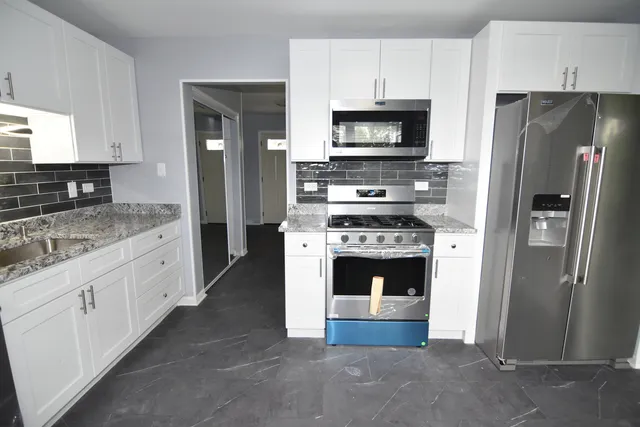 a kitchen with granite countertop cabinets stainless steel appliances and a wooden floor