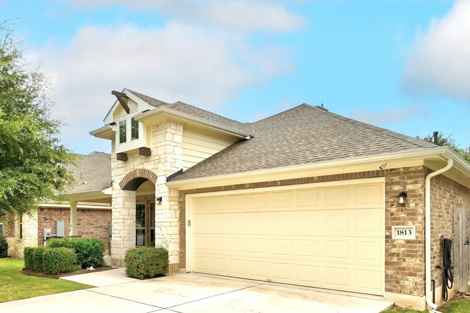 1813 Chickasaw Run Leander, TX 78641 - Photo 1 of 32 A welcoming facade showcases a mix of brick and stone with an arched entryway and attached garage.