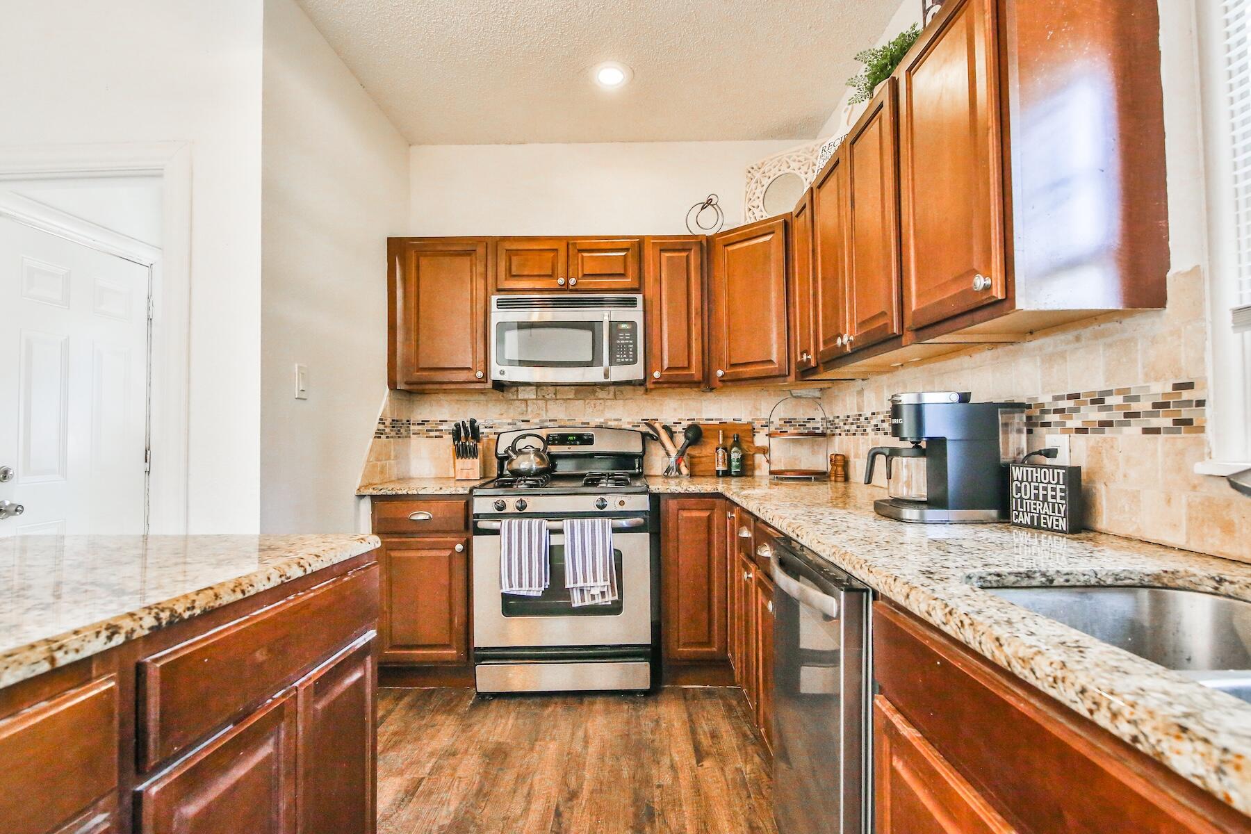 2309 17th Street Lubbock, TX 79401 - Photo 7 of 26 a kitchen with stainless steel appliances granite countertop a stove a sink and a microwave