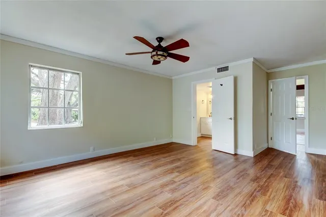 a view of an empty room with window and wooden floor
