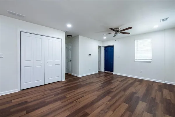 a view of empty room with wooden floor and fan