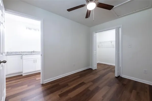 an empty room with wooden floor chandelier fan and windows