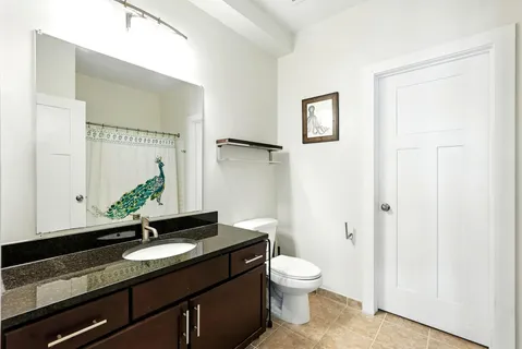 a bathroom with a granite countertop sink toilet and mirror