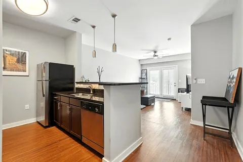 a kitchen with stainless steel appliances granite countertop a refrigerator a stove and a wooden floors