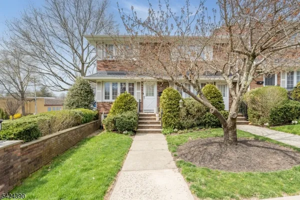 a front view of a house with a garden and trees