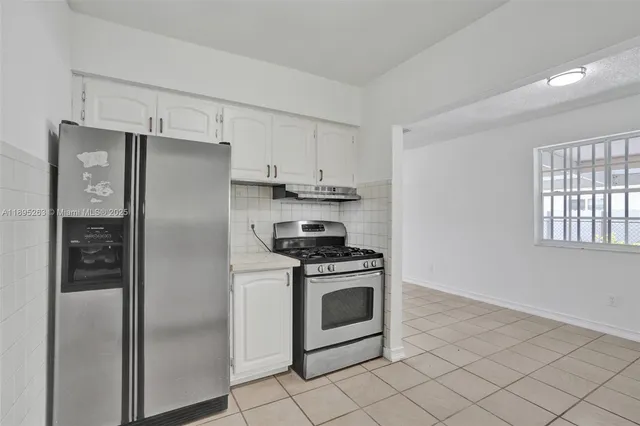 a kitchen with cabinets stainless steel appliances and a window