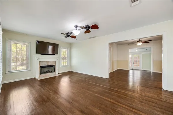 a view of a livingroom with a fireplace a ceiling fan and wooden floor