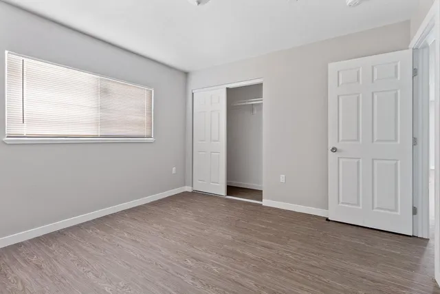 a view of an empty room with wooden floor and a window