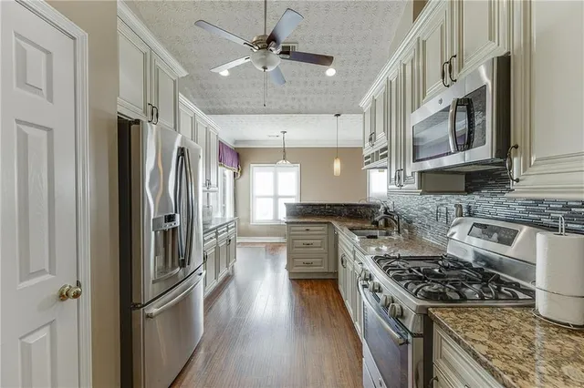 a kitchen with stainless steel appliances granite countertop a stove top oven a refrigerator a sink and dishwasher