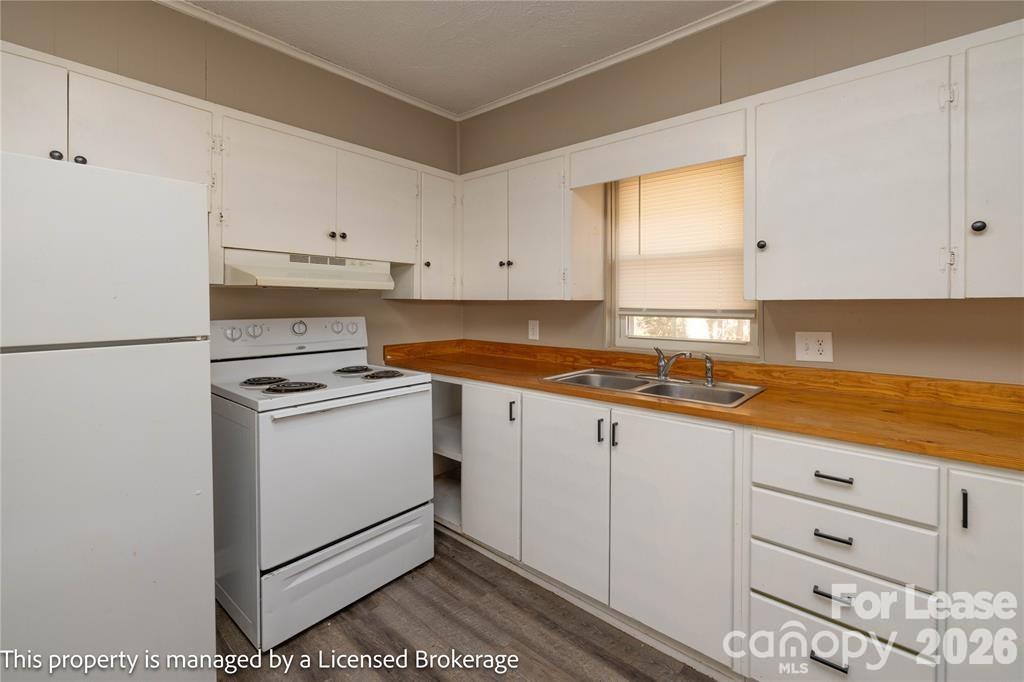 213 Roslyn Road Troy, NC 27371 - Photo 12 of 25 a kitchen with granite countertop white cabinets and white appliances