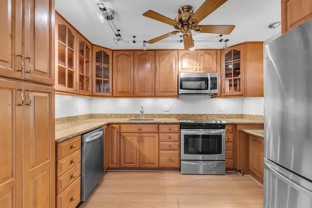 a kitchen with stainless steel appliances granite countertop a stove top oven a refrigerator and a sink