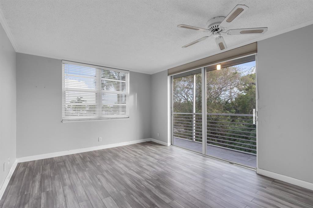 4020 West Palm Aire Drive, Unit 312 Pompano Beach, FL 33069 - Photo 20 of 36 an empty room with wooden floor fan and windows