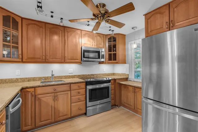 a kitchen with stainless steel appliances granite countertop a refrigerator a sink dishwasher a stove with wooden cabinets