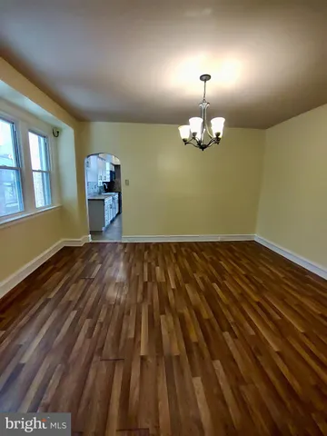 a view of a room with wooden floor chandelier and a window