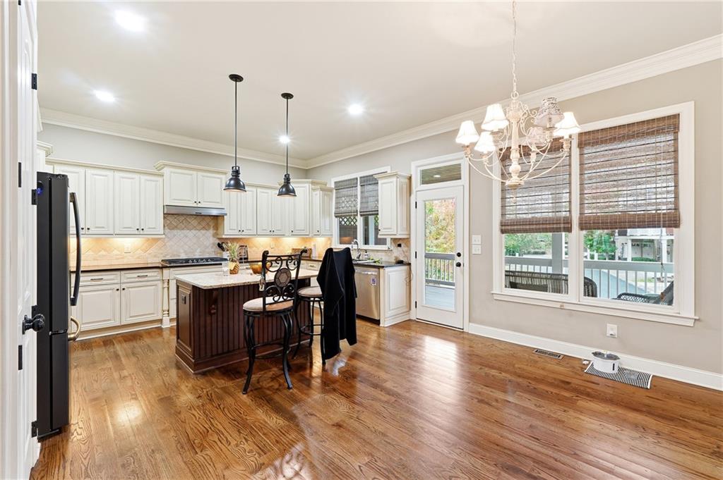 265 Trecastle Square Canton, GA 30114 - Photo 15 of 47 a kitchen with kitchen island granite countertop wooden floors refrigerator and dining table