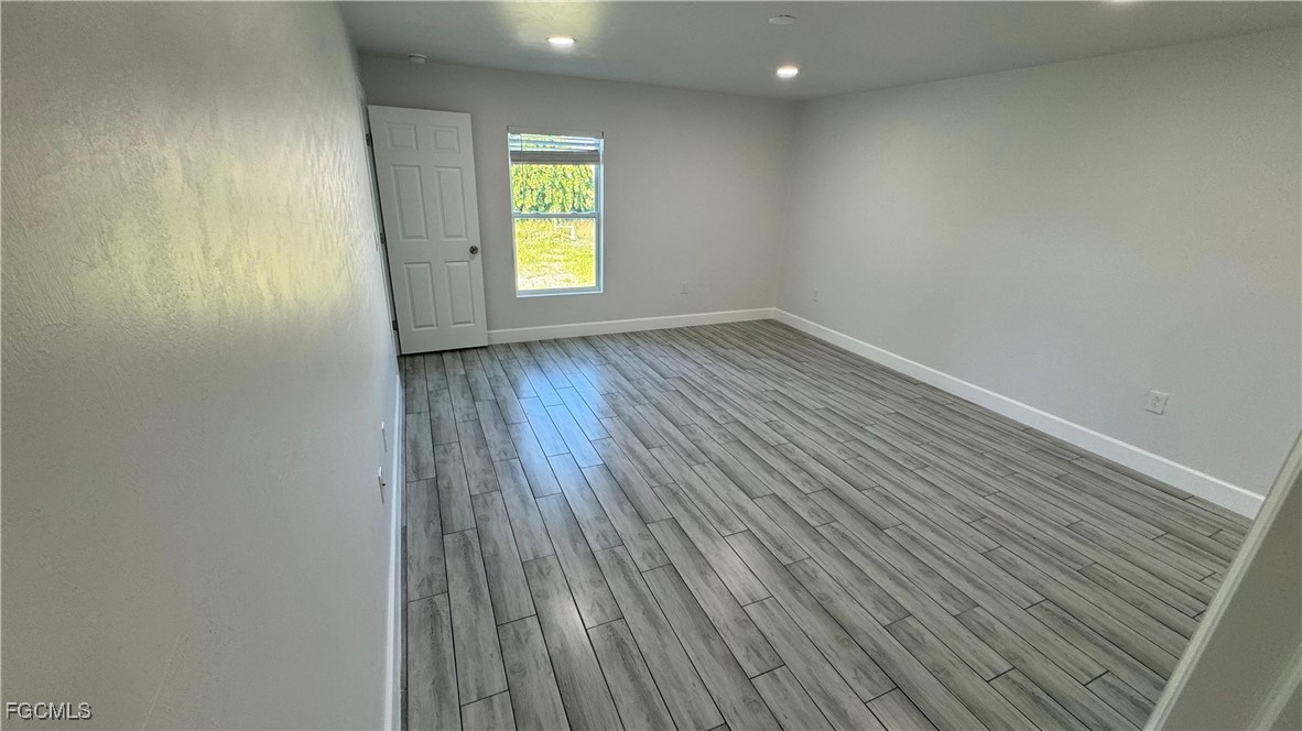 3314 36th Street Southwest Lehigh Acres, FL 33976 - Photo 19 of 23 a view of an empty room with a window and wooden floor