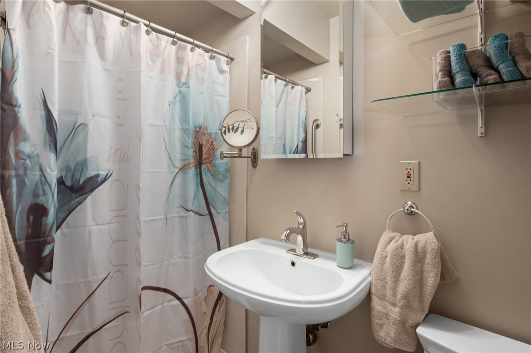 685 Sunnyside Road Vermilion, OH 44089 - Photo 26 of 50 Pedestal sink with chrome faucet, wall-mounted medicine cabinet, and glass shelving