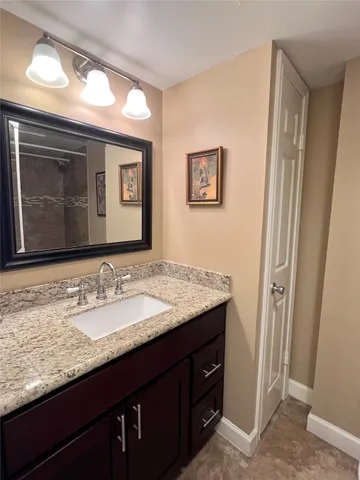 a bathroom with a granite countertop sink vanity and mirror