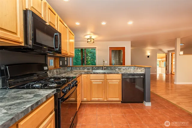 a kitchen with stainless steel appliances granite countertop a stove a sink and a microwave