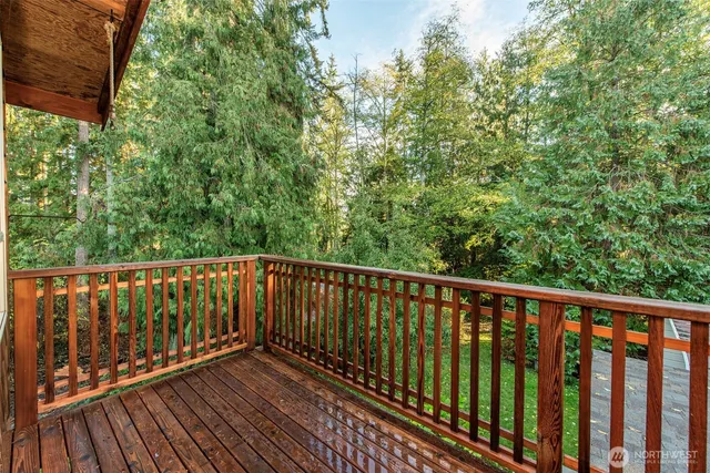 a balcony with wooden floor and trees in the back