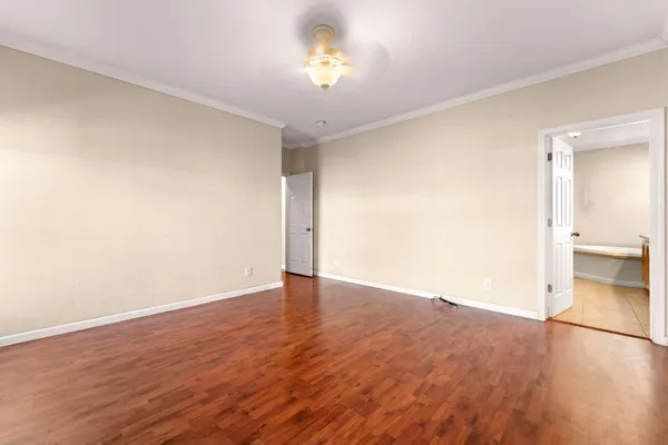 an empty room with wooden floor and bathroom