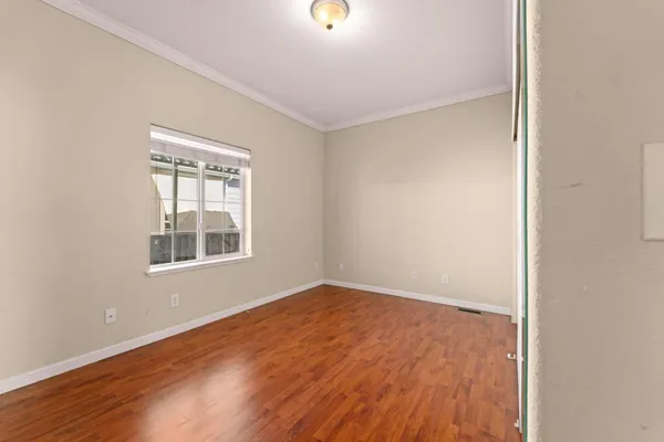 an empty room with wooden floor and windows