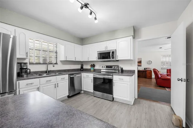 a kitchen with a sink cabinets appliances and a window