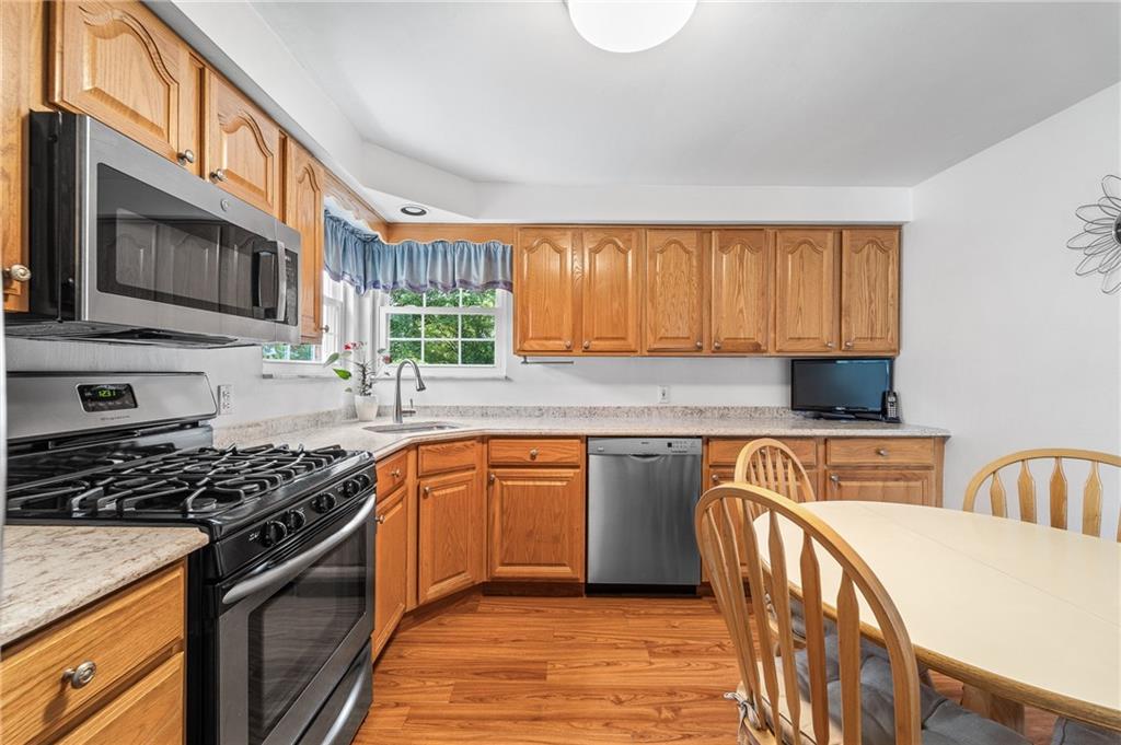 239 Roberts Road Pittsburgh, PA 15239 - Photo 10 of 30 a kitchen with stainless steel appliances granite countertop a stove a sink dishwasher and a microwave oven with wooden cabinets