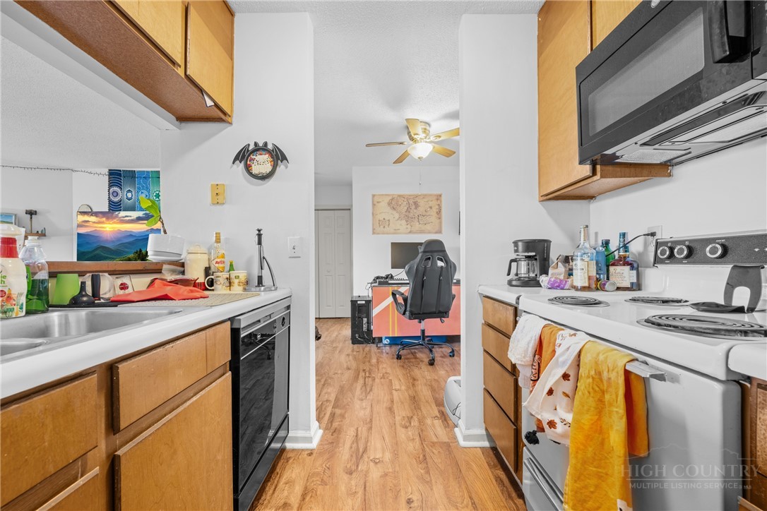 200 Pilgrims Way, Unit 12 Boone, NC 28607 - Photo 11 of 21 a kitchen with stainless steel appliances granite countertop a sink dishwasher stove refrigerator and couches with wooden floor